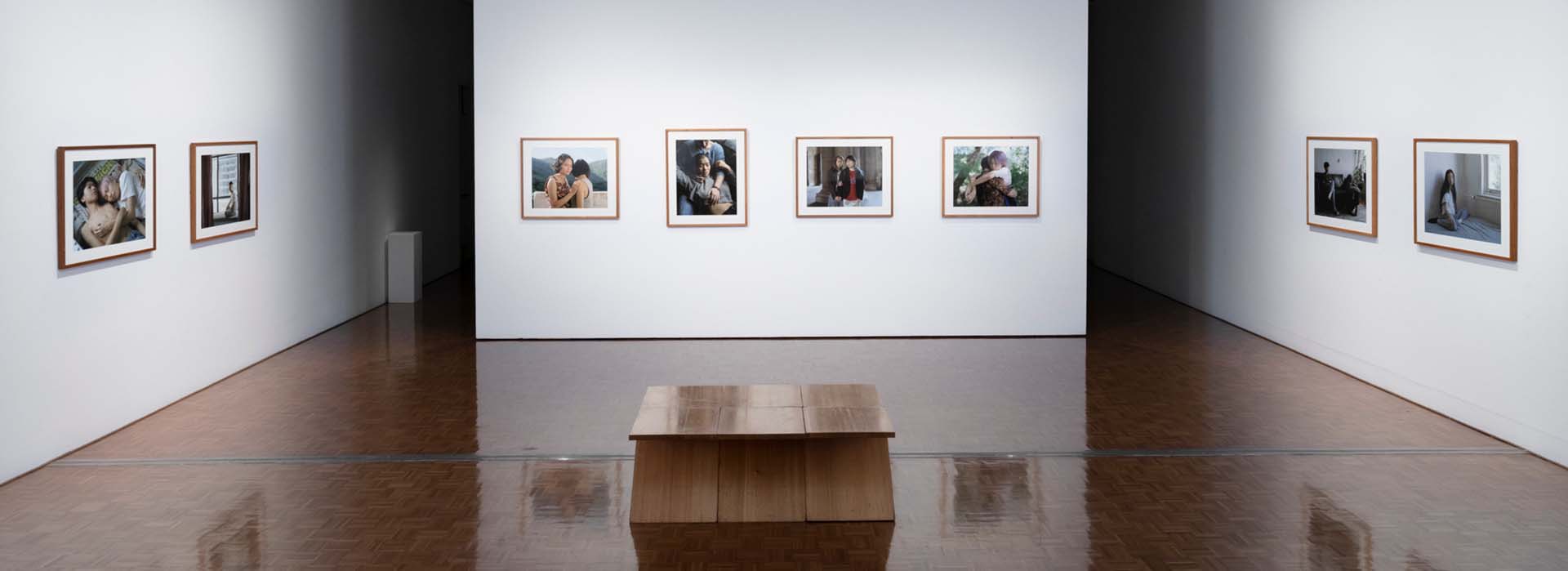 An exhibition of photographs in the Delmar gallery with a wooden bench.