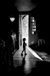 Black and white photograph of a child walking through a doorway.