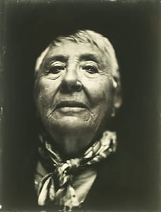A black and white photo of an old woman with a scarf.