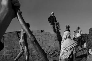 A black and white photo of a group of people working on a building.