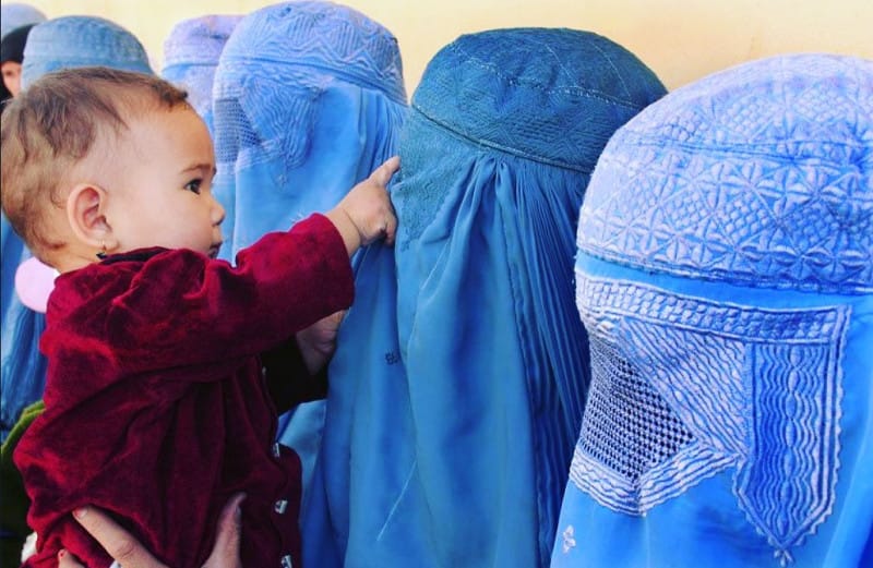 young child pointing at females in a burqa