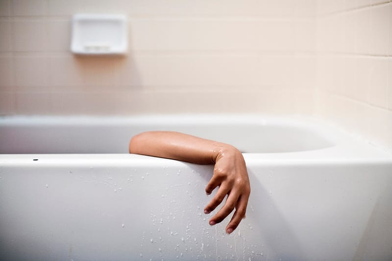 Arm hanging out the side of a bathtub
