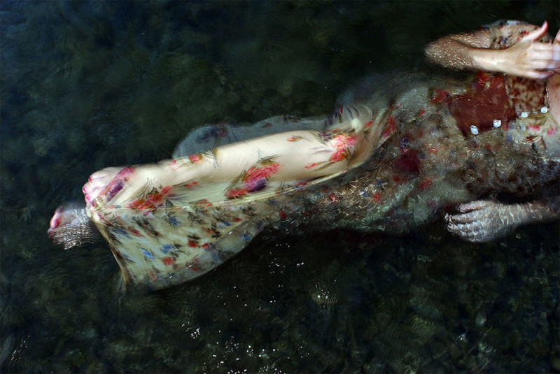 A woman in a floral dress floats in water